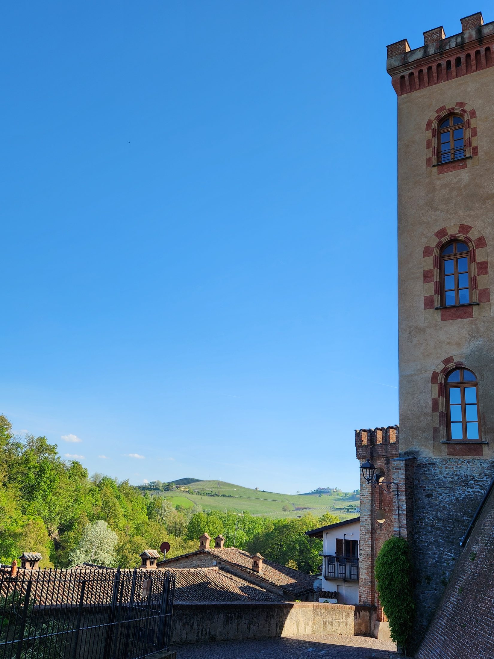 Tour crénelée du château de Barolo, façade ocre et fenêtres à arcs, ciel bleu