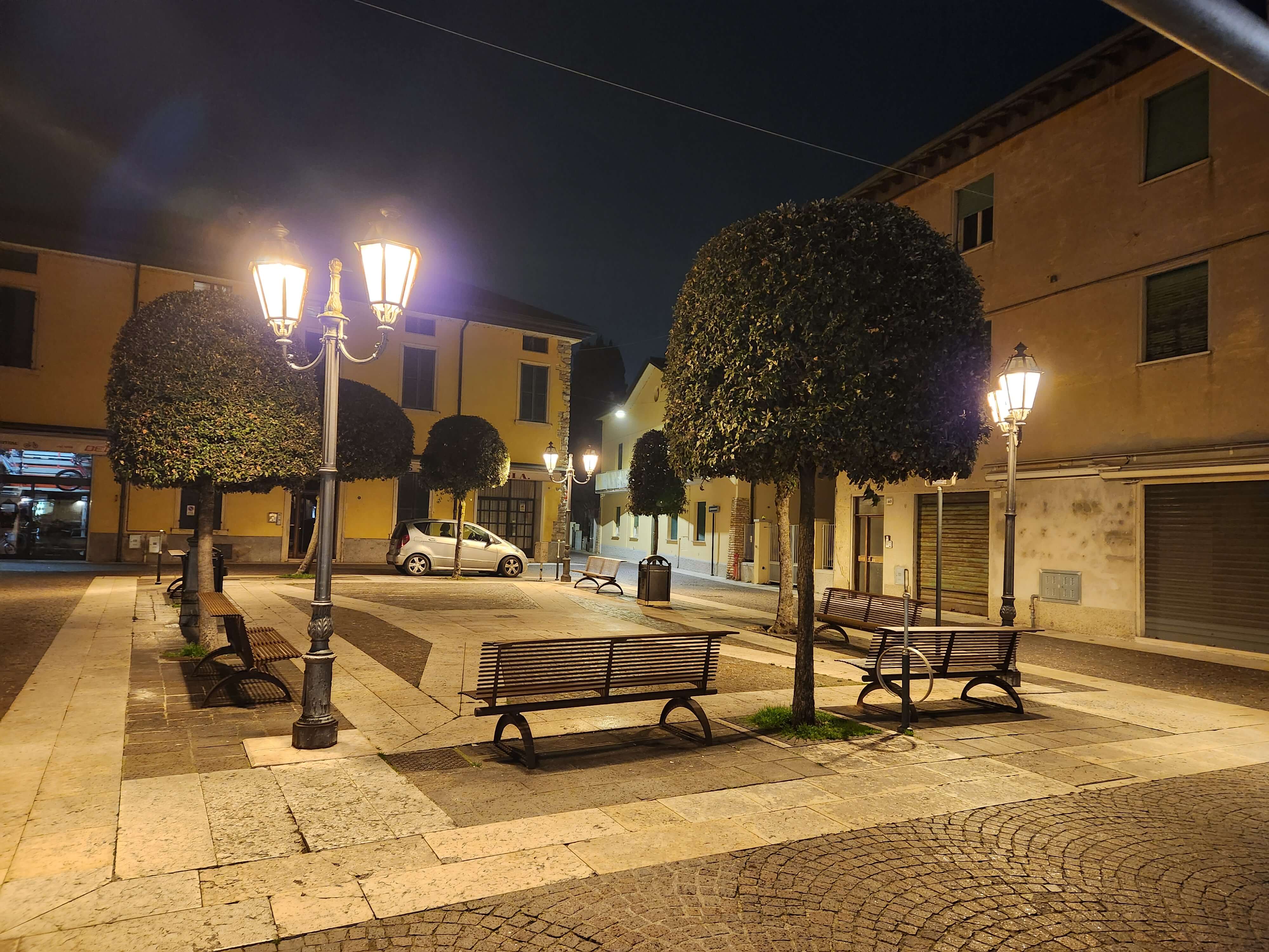 Place de Lazise la nuit, lampadaires et arbres taillés, lac de Garde