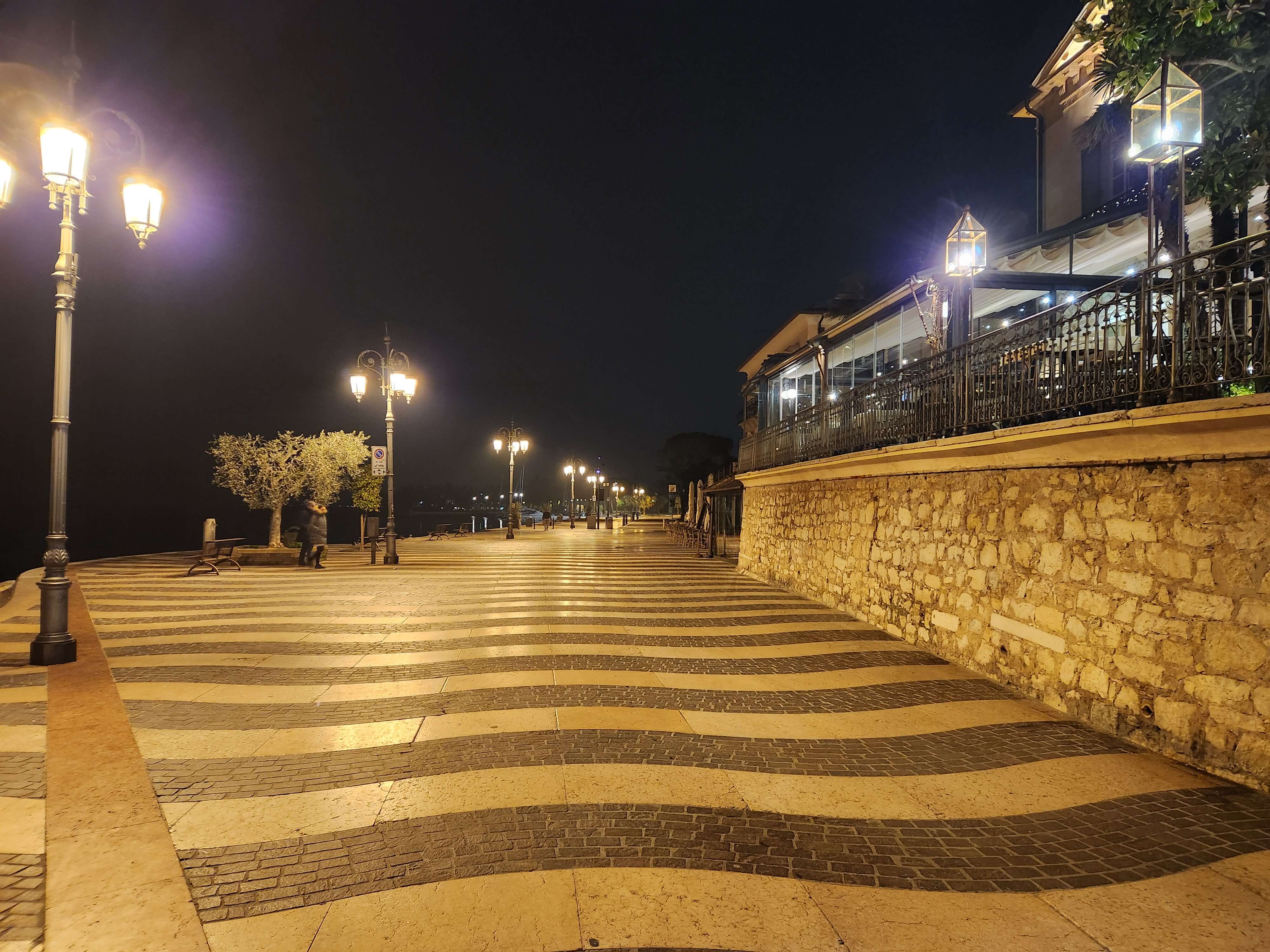 Promenade du lac de Garde à Lazise la nuit, lampadaires et pavés en vagues