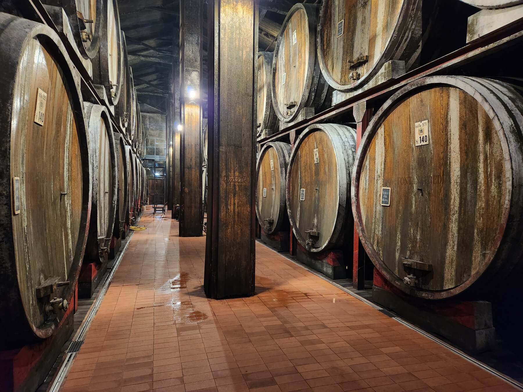 Cave aux foudres anciens empilés sur plusieurs niveaux, domaine viticole du Piémont