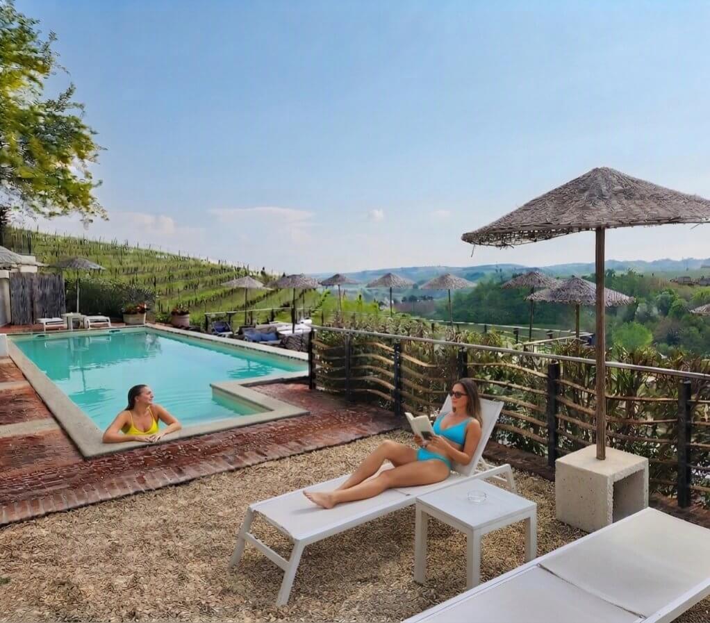 Piscine extérieure avec parasols face aux vignobles des Langhe, resort viticole du Piémont