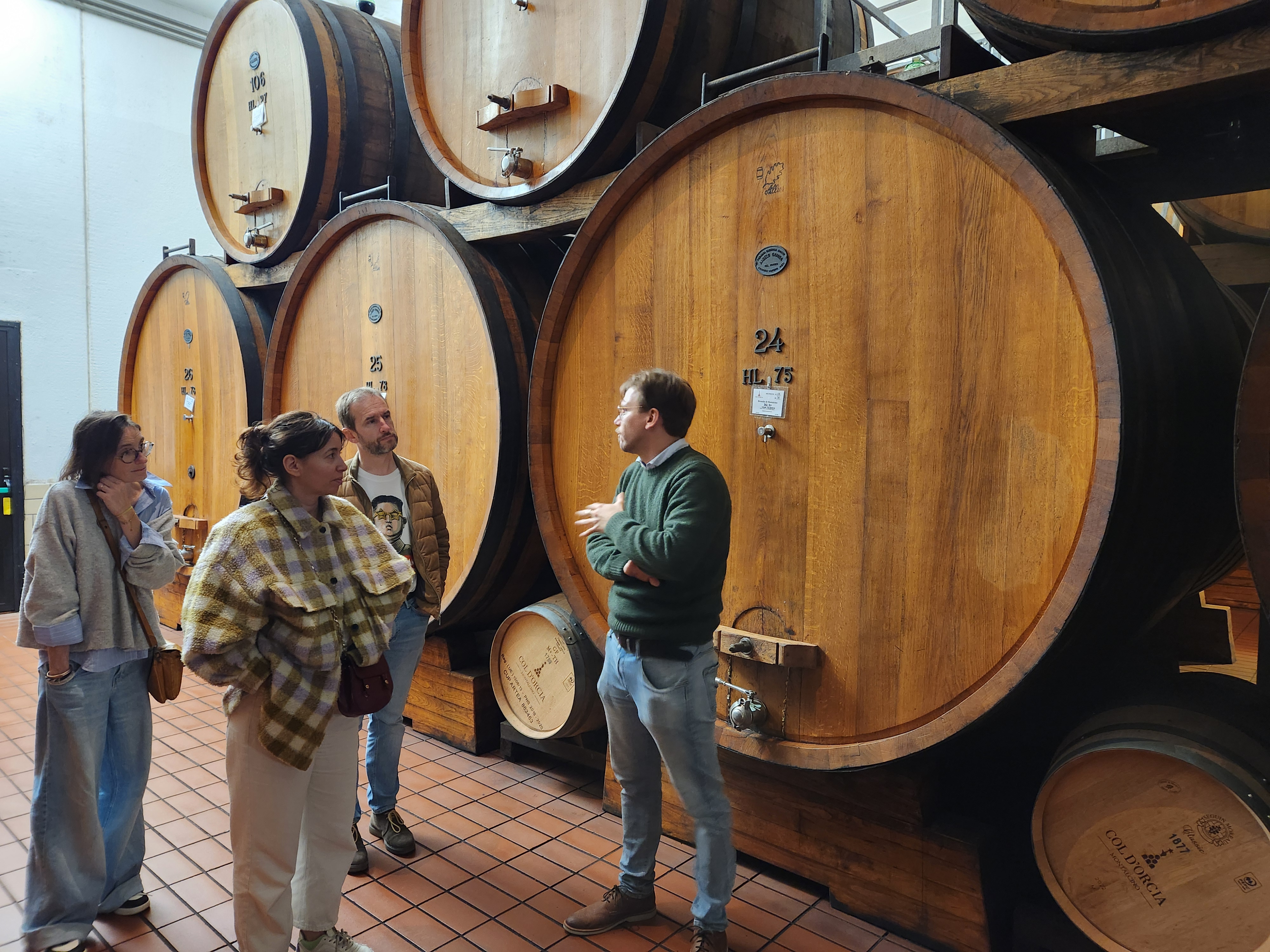 Le vigneron explique le processus d'élevage du Brunello devant les grands fûts de chêne
